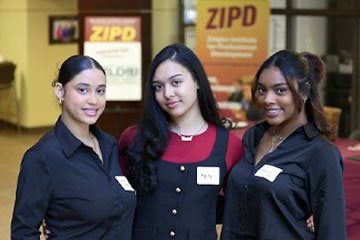 Three female student pose for phot during ZIPD Business Conference in 2025.