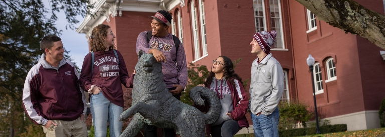 A group of Bloomsburg students talking and laughing near at the Husky statue 