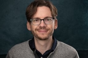 A photo of playwright Dano Madden, looking gently into the eyes of the viewer.