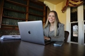A CU-Mansfield Political Science Pre-Law student at her internship in a local law firm sitting at a conference table at a laptop