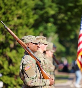 Military soldier holding rifle on shoulder.