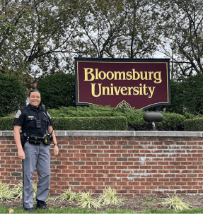 Jennifer Kobe stands next to the Bloomsburg University sign on a recent visit to recruit on campus.