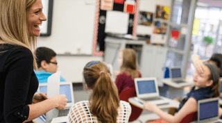 A teacher overlooking her students working.