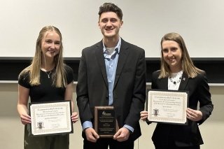 Three people standing with awards.