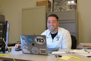 Bryson Purcell sitting at a desk looking at his laptop.