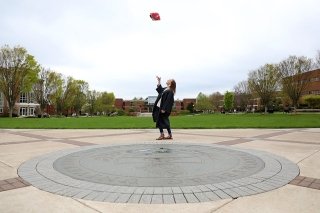 A girl throwing a cap in the air.