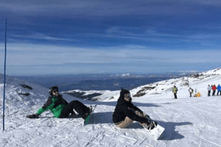 Two people sitting in the snow.