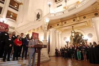 A man standing behind a podium with a crowd in a very nice building.