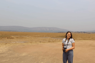 A woman with a camera standing outside. 