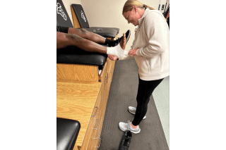 An image of a woman wrapping someone's foot. 