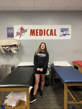 Taylor Johns standing between to medical (chiropractic) beds.