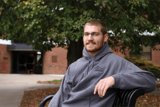 A man leaning back on a bench outside.