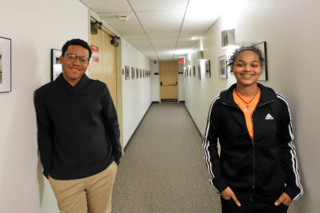 Two people leaning against a hallway wall. 