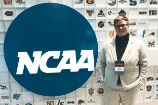 A person standing next to a NCAA sign.