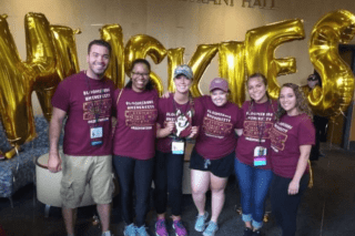 A group standing in front of gold balloons.