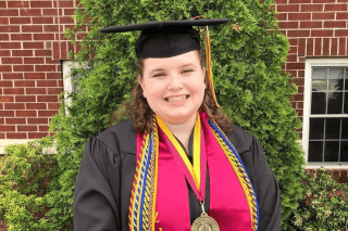 A headshot of a woman in her graduation cap and gown.