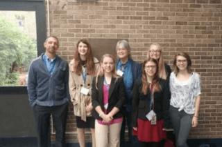 A group of people standing together in front of a brick wall.