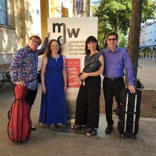 Four people standing side by side around a poster. 