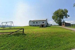 The exterior of a building with a tree and a swingset. 