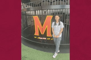 A girl standing next to an M. 