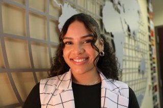 An International Business student at CU-Bloomsburg stands in front of a large world sign at Sutliff Hall in CU's Zeigler College of Business