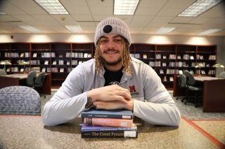 A Secondary Education major at CU-Mansfield in the library at North Hall with a stack of books