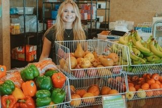 A CU student poses with a selection of fresh fruits and vegetables
