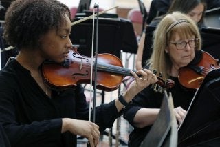 Sanai Castle playing violin with the orchestra.