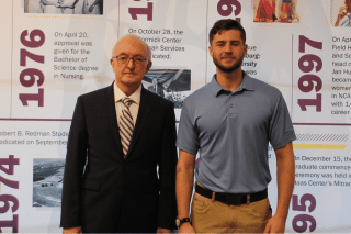 Alum volunteer, Tom Stiner '77 stands with a current Bloomsburg student