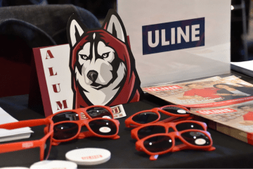 Uline sign and Husky Alumni sign on the information table for Uline