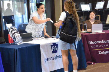 Julie Tressler hands a student her business card at one of the Career Expos on the Bloomsburg campus
