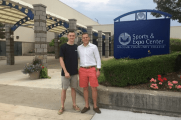 Two men standing in front of a sign that says, "Sports and Expo Center."