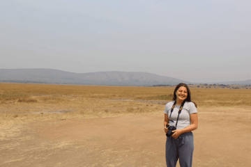 A woman with a camera standing outside. 