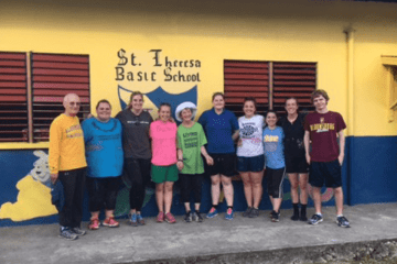 A group standing in front of a yellow building. 