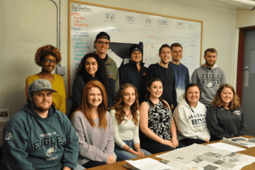 A group standing in front of a white board. 