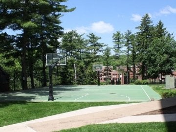 Outdoor basketball court surrounded by trees behind Columbia Hall