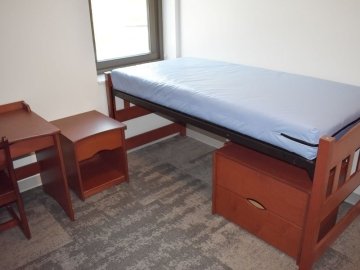Bed, night stand and desk in a bedroom in David Soltz Hall