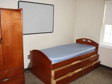 Bedroom of Jessica Kozloff Apartments showing bed with under bed storage, a closet and window