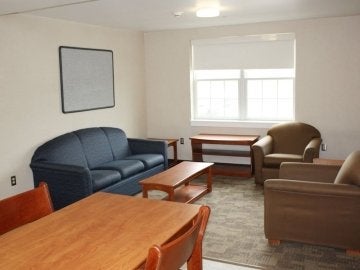 Living rooom in a Jessica Kozloff Apartment with two chairs, a couch, coffee table and kitchen table