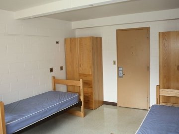 Bedroom in Luzerne Hall showing two beds, two closets and the door.