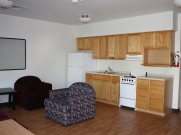 Living room / kitchen showing cabinets, sink, refrigerator, range and seating in the Mount Olympus Apartments