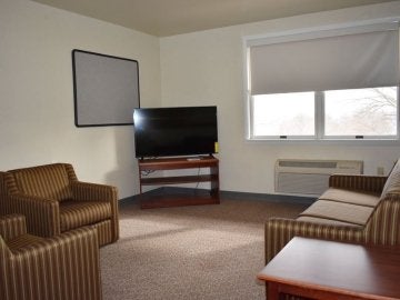 Living room of Montgomery Place Apartments showing chairs, couch, table, tv and stand, window and A/C unit