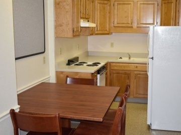 Kitchen in the Montgomery Place Apartments showing a range, refrigerator, sink and kitchen table.