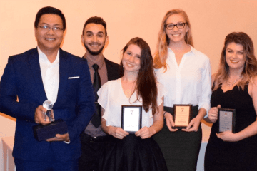 A group of people standing together with awards.