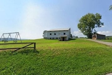 The exterior of a building with a tree and a swingset. 