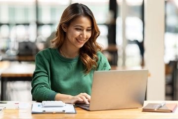 Female wearing green sweater working on laptop