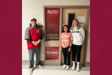 Three people standing around a sign. 