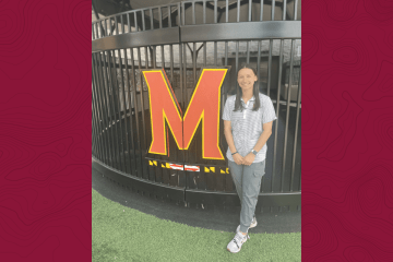 A girl standing next to an M. 