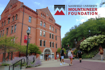 Students walk on the Commonwealth University-Mansfield campus in front of North Hall with the Mansfield University Mountaineer Foundation logo