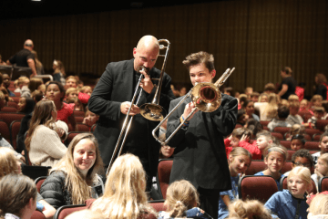 A CU-Bloomsburg Music student and faculty member entertain a large crowd of elementary students playing the trombone in Haas Auditorium